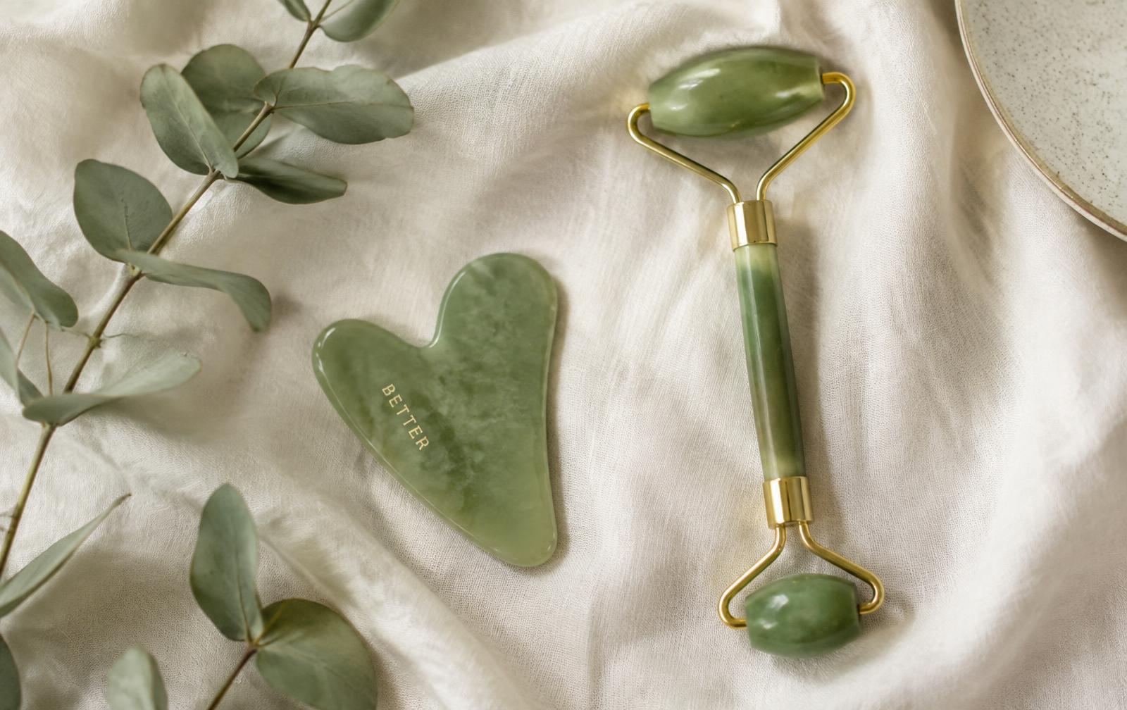 Jade gua sha stone and jade roller on ivory linen